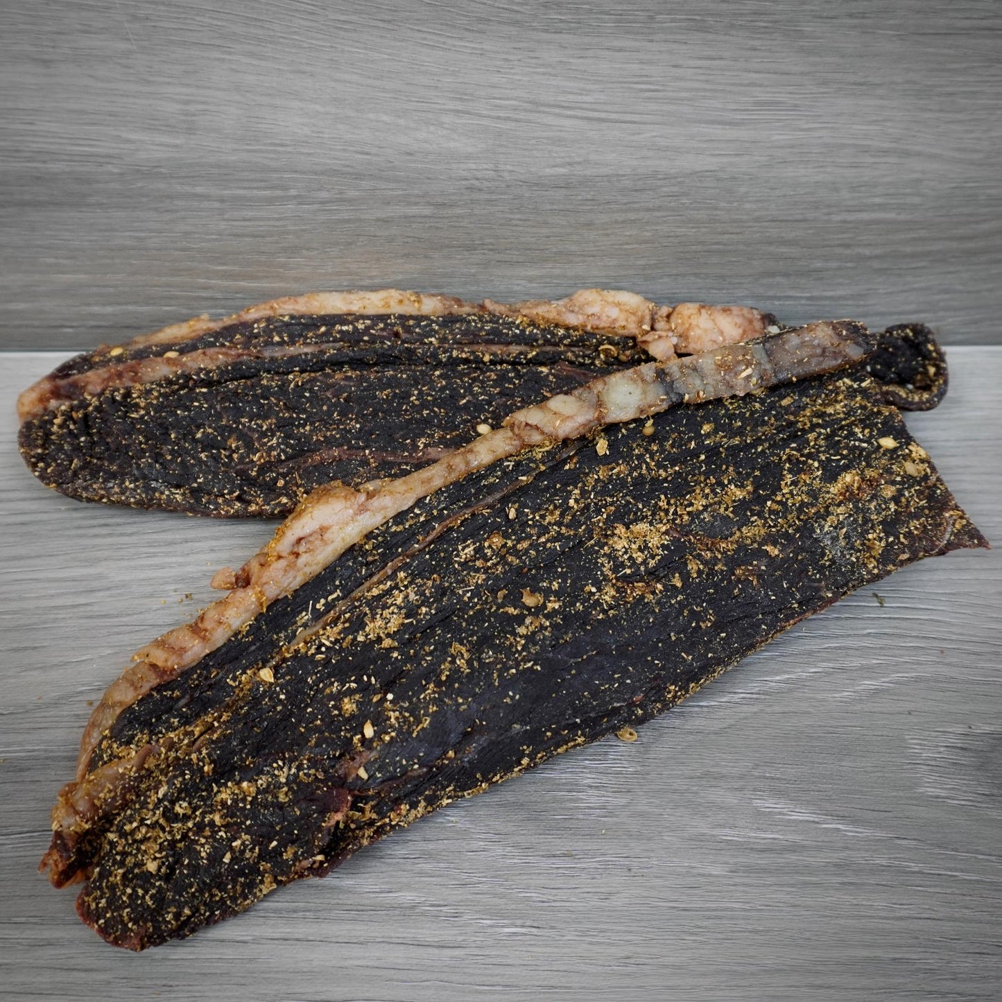 Two pieces of dried meat on a metallic surface