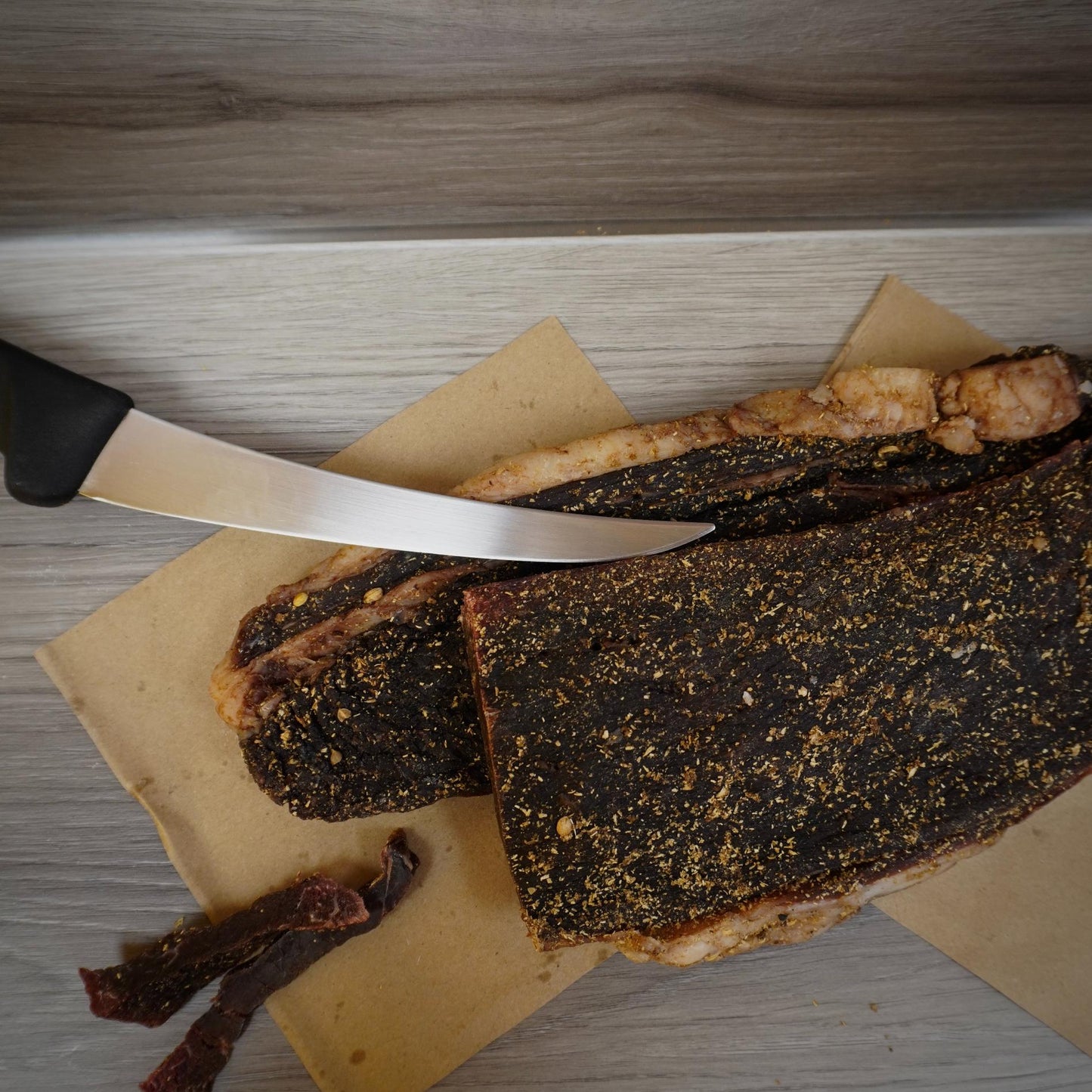 Dried meat with a knife on a wooden cutting board