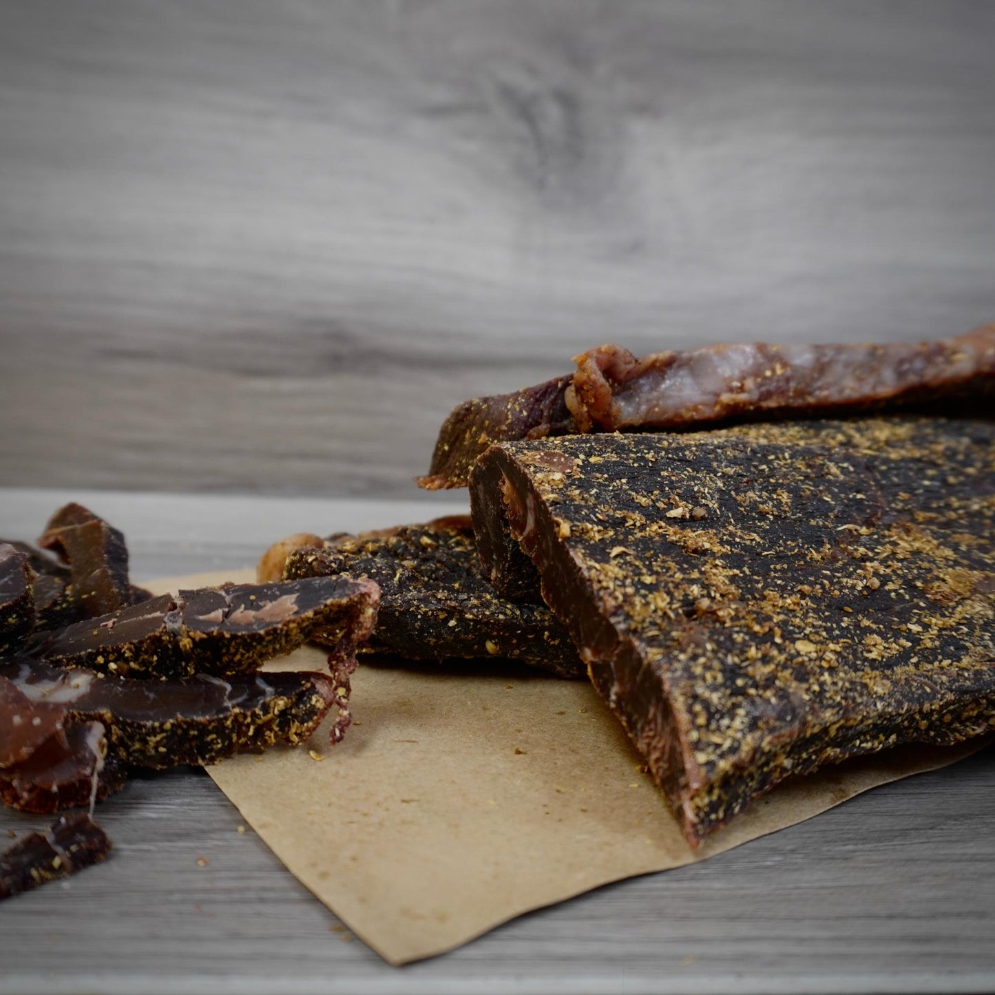 Dried meat strips on a wooden surface with a gray background