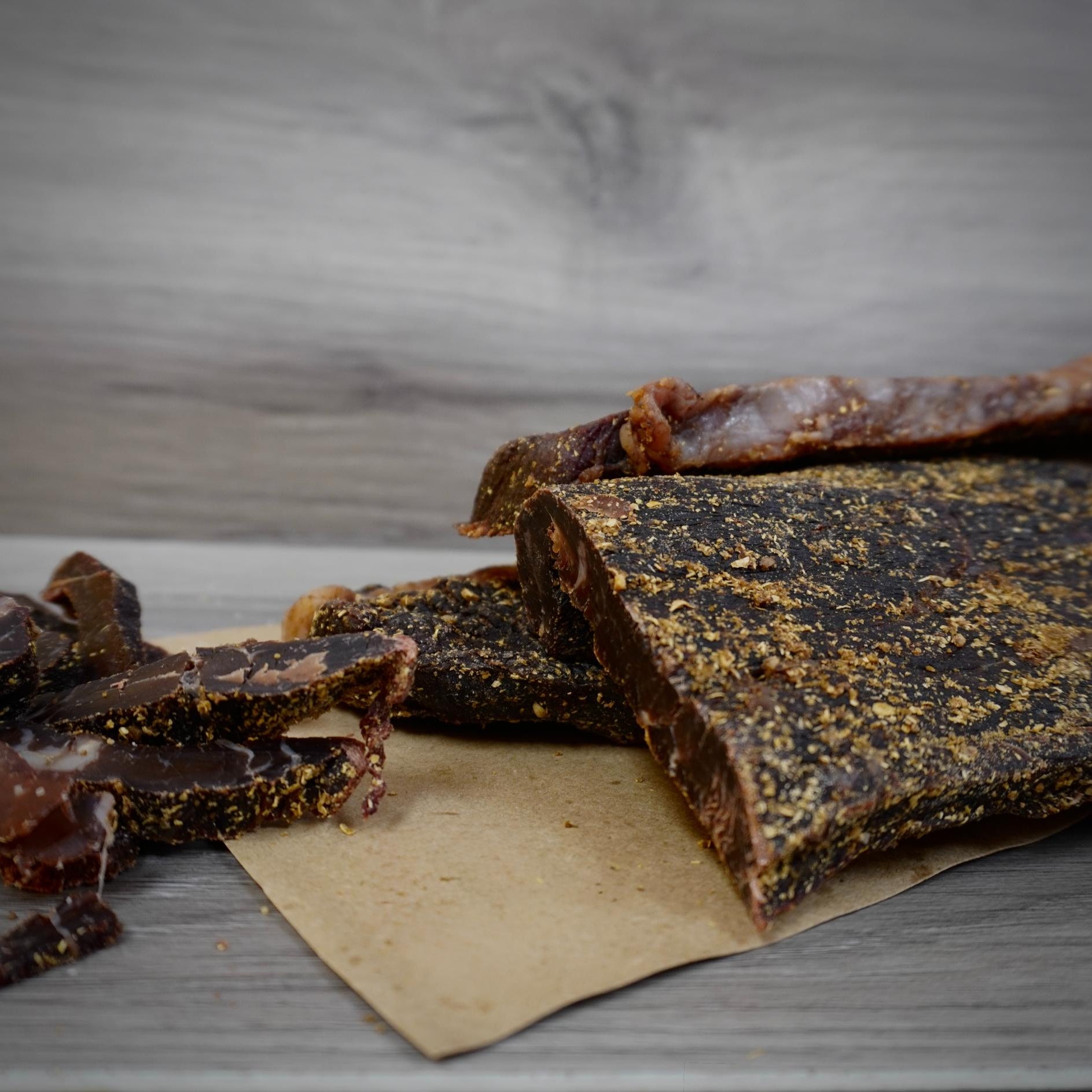 Dried meat strips on a wooden surface with a gray background