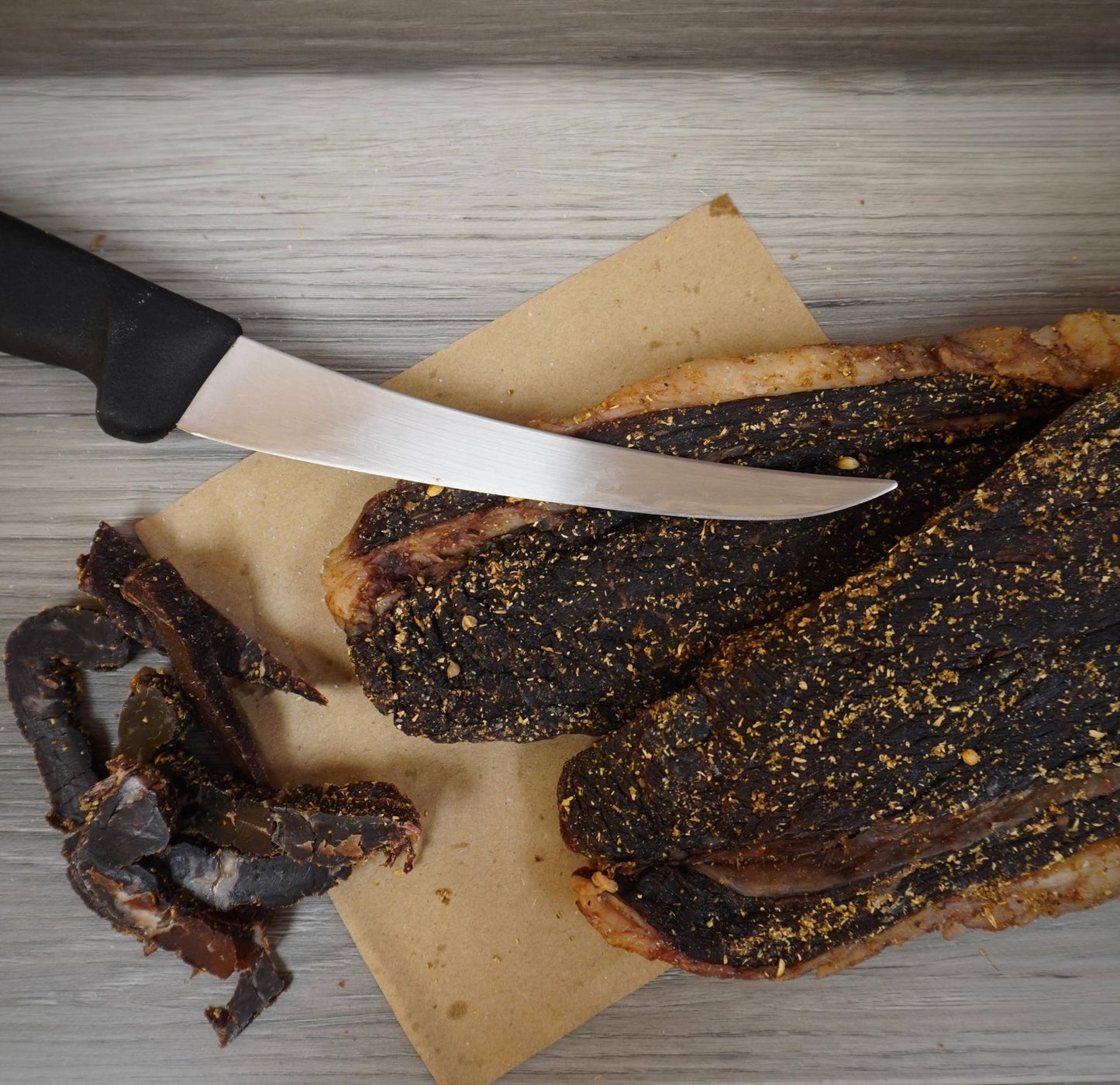 Dried meat slices on a cutting board with a knife