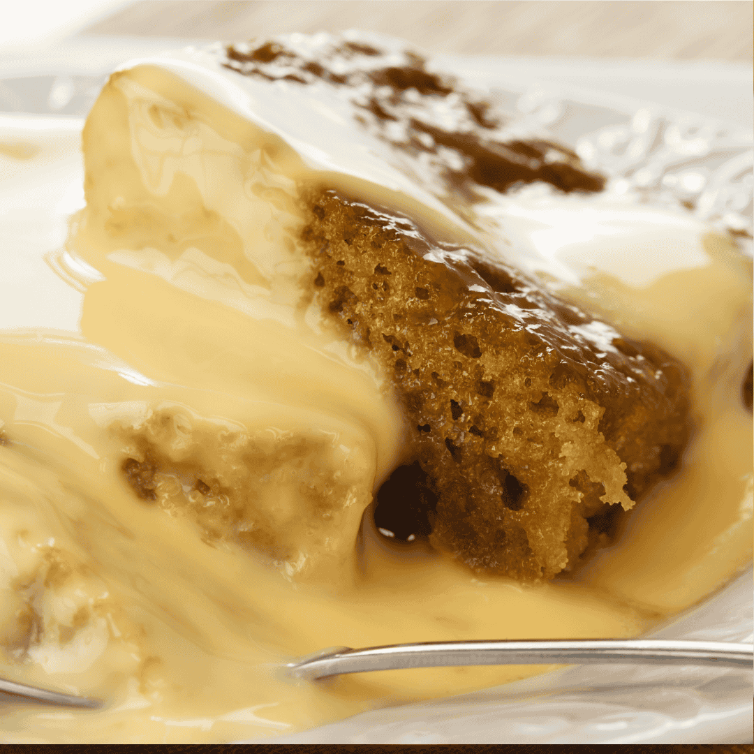 Slice of malva pudding with custard on a plate